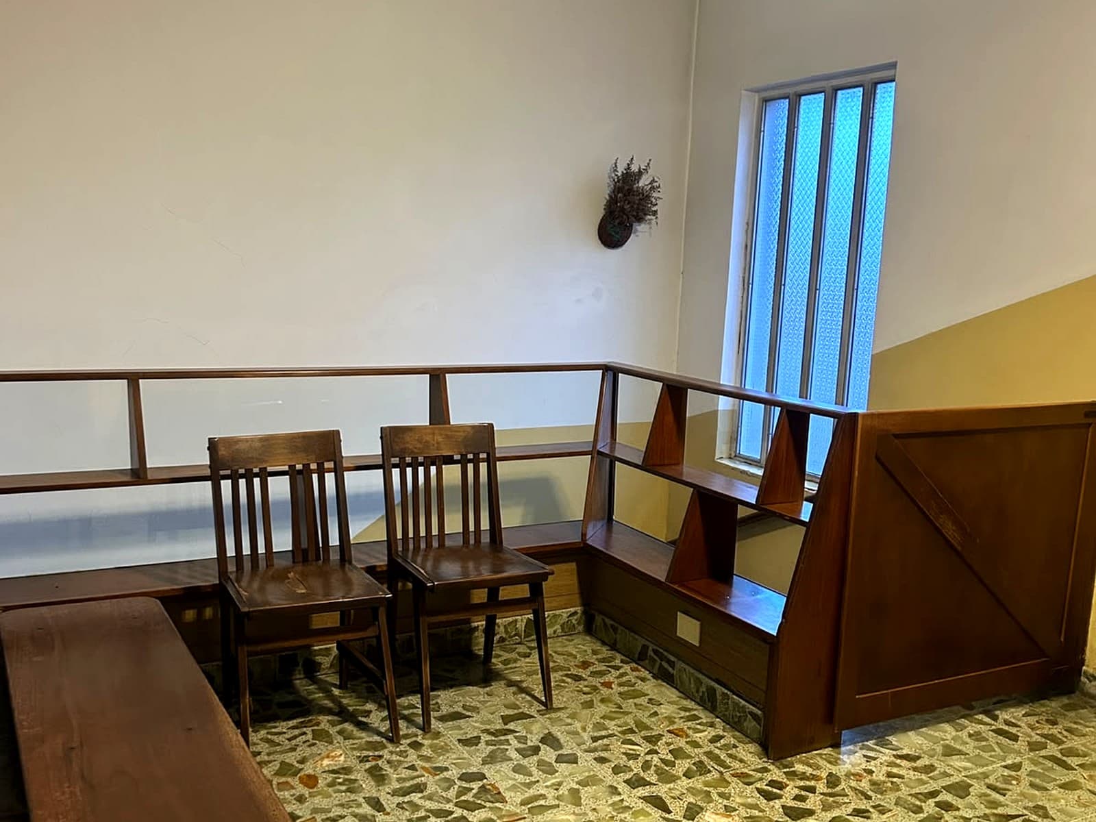 Sala de espera del estudio, con sillas y bancos de madera junto a una ventana alta